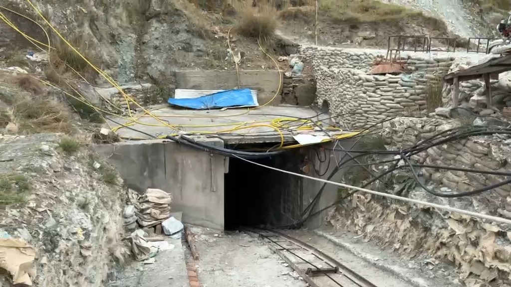A concrete-framed mine adit with narrow-gauge rail track running into it